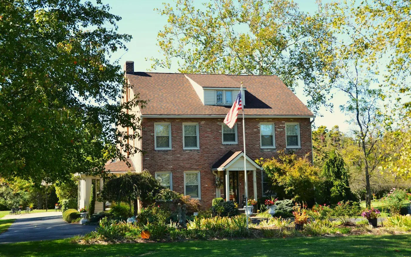A brick family home with an American flag on the lawn